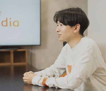 会議をしている人物の写真。ラフな装いと自然な笑顔が印象的なオフィスシーン。